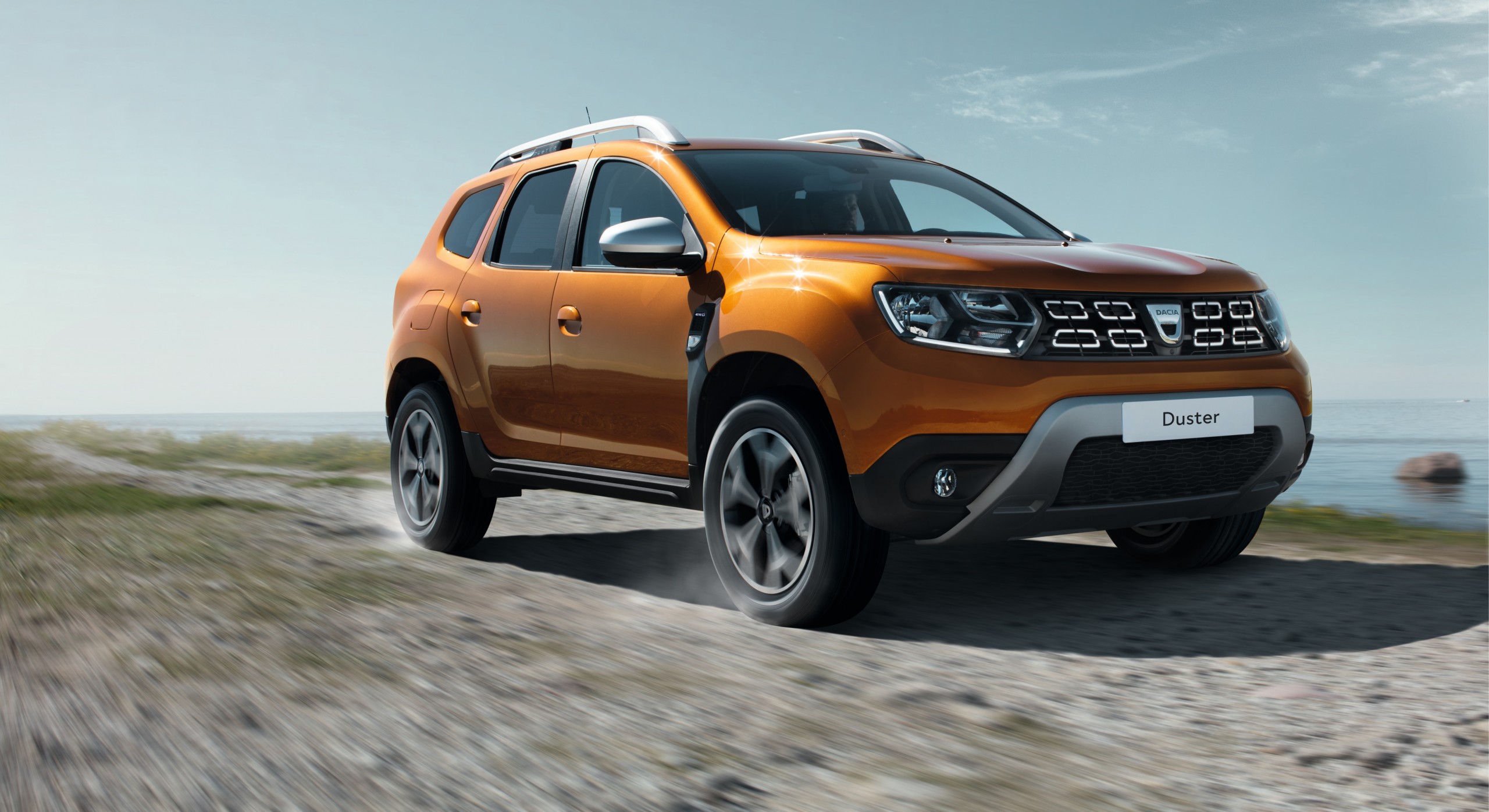 Novo Renault Dacia Duster na cor laranja em movimento com grade com nichos retangulares e a logo da romena Dacia