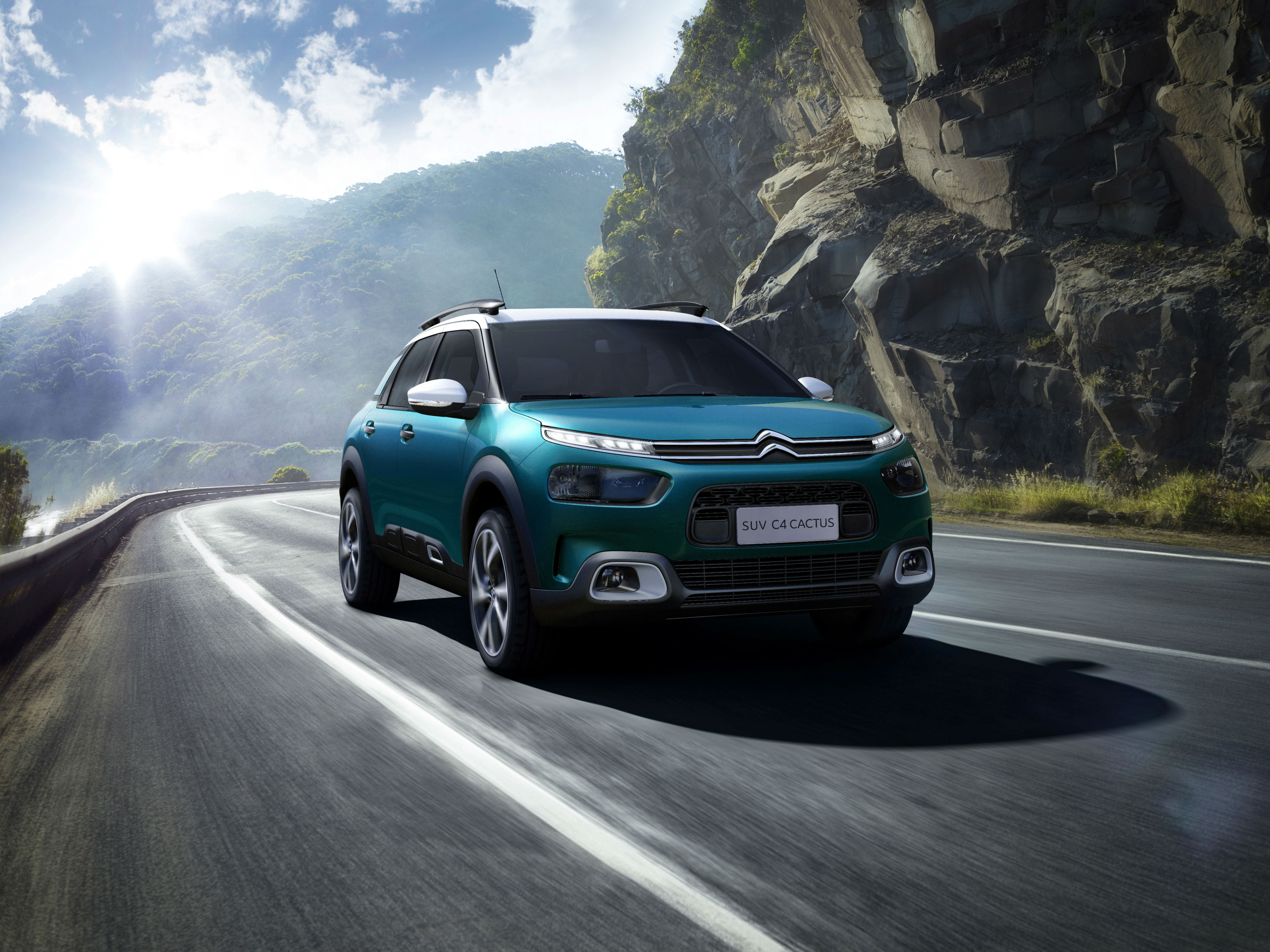 Citroën C4 Cactus azul em movimento na estrada com teto e molduras dos faróis de neblina na cor branca