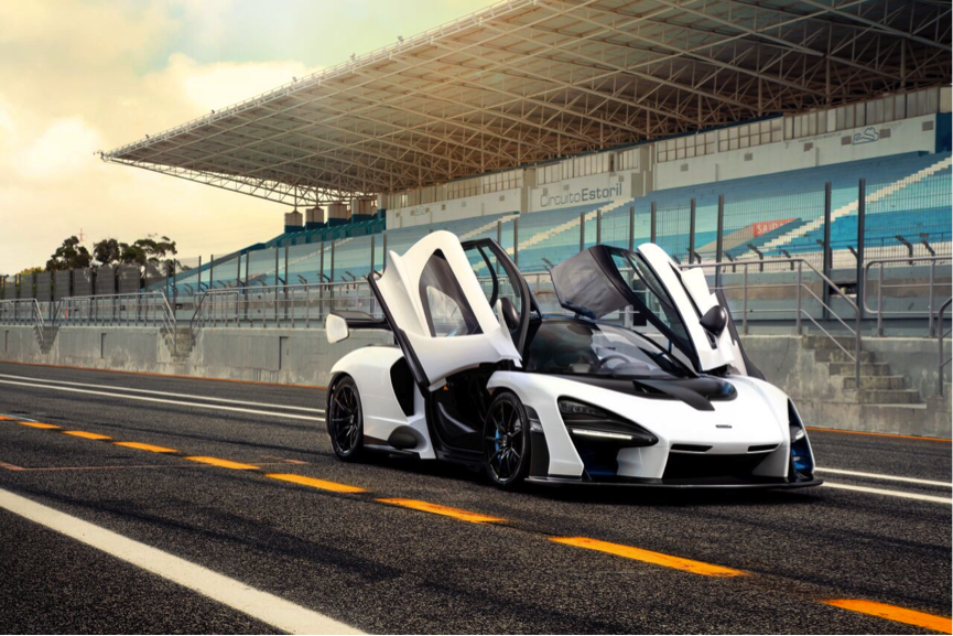 McLaren Senna na cor branca parado em um circuito fechado e com as portas do tipo tesoura levantadas