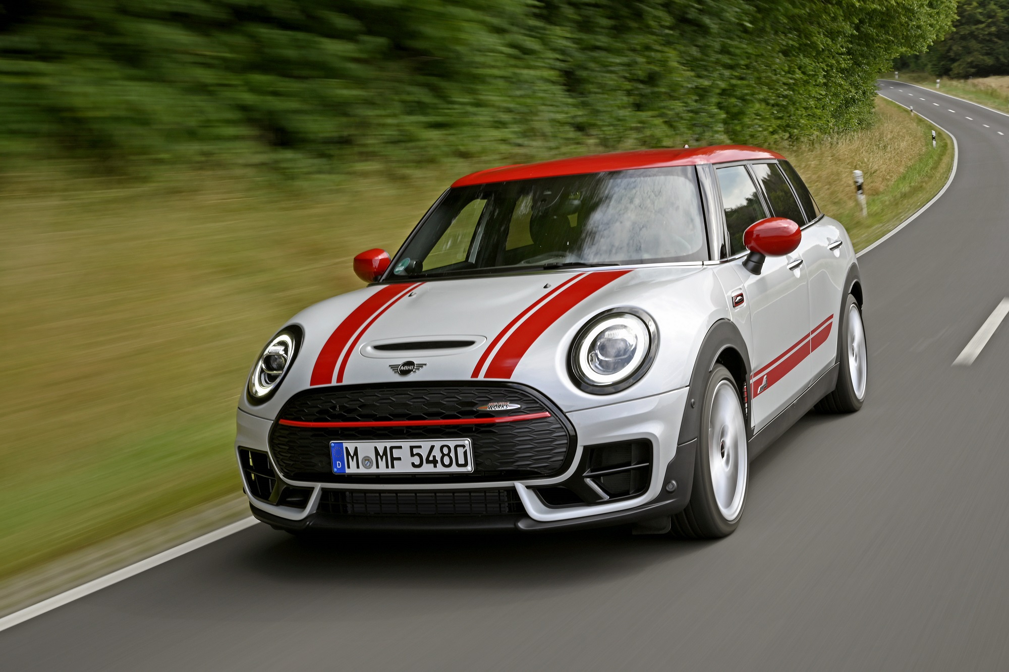 Mini Clubman John Cooper Works branco com faixas vermelhas e visual esportivo em movimento