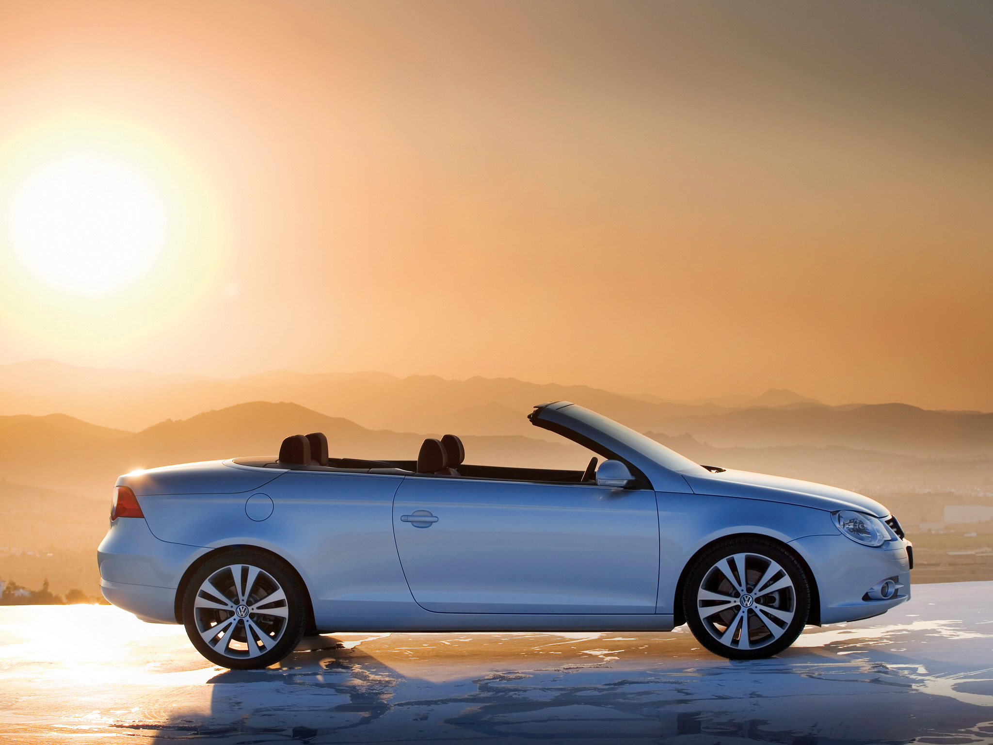 Volkswagen Eos de perfil e capota aberta com o sol se ponto ao fundo