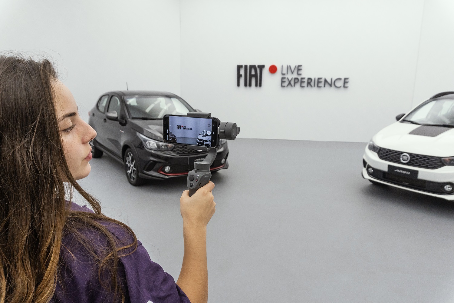 Especialista da Fiat mostra o Fiat Argo com um celular e um estabilizador de câmera