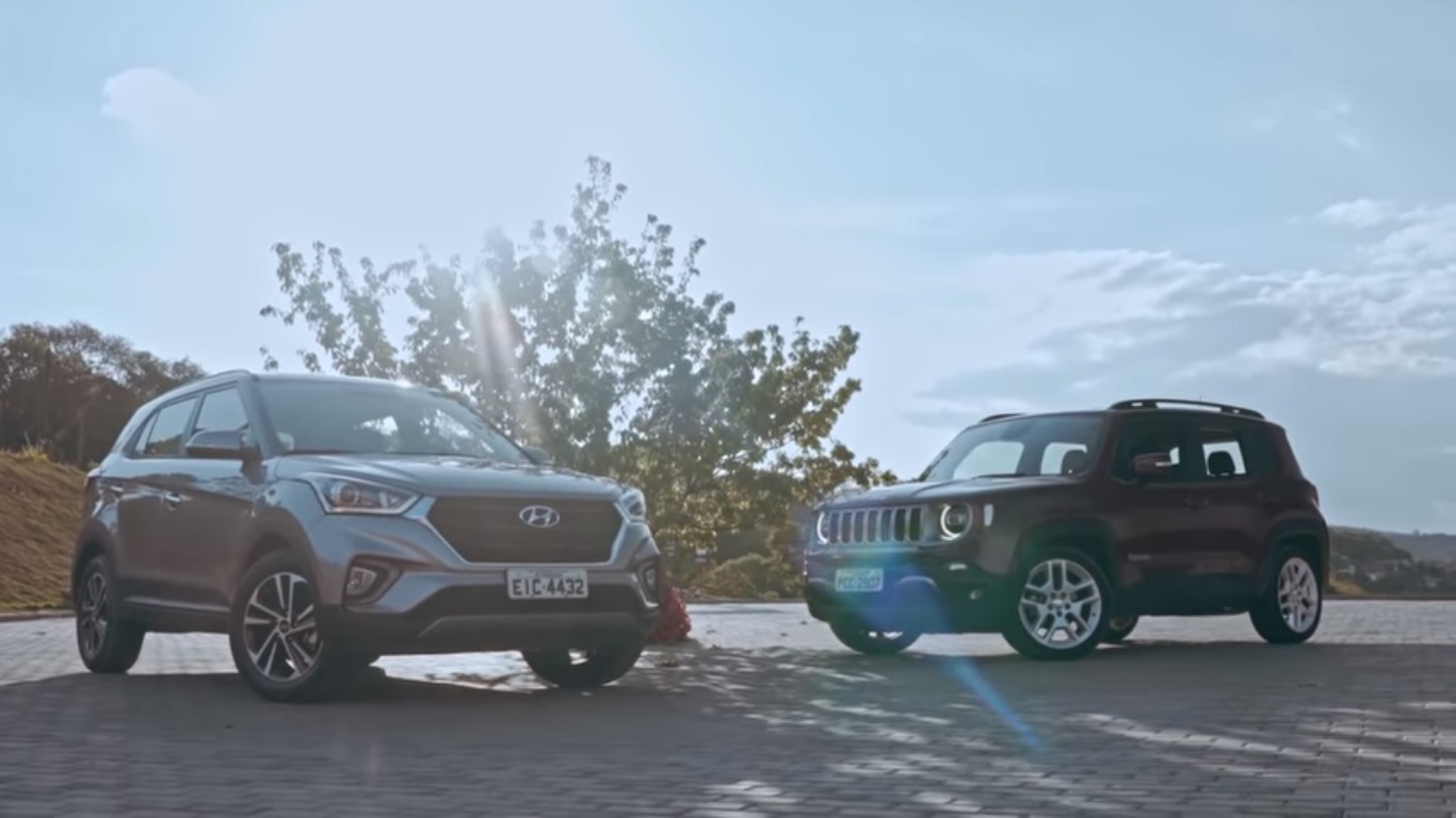 Creta e Renegade, ambos na diagonal, em ambiente natural com luz do sol refletindo entre eles
