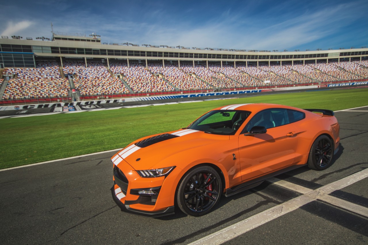 Ford Mustang Gt500 na cor laranja de perfil em um autódromo