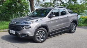 Fiat Toro de frente na cor verde tendo ao fundo vegetação e uma praia