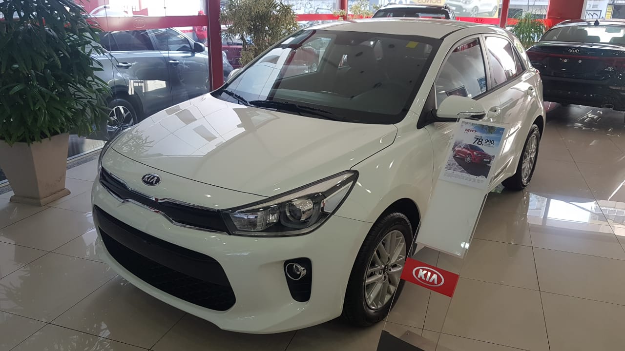 Kia Rio Ex na cor branca de frente em uma loja da marca