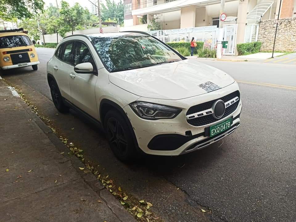 nova mercedes gla na cor branca de frente estacionada na rua e com adesivos que cobrem a marca da estrela e a grade frontal
