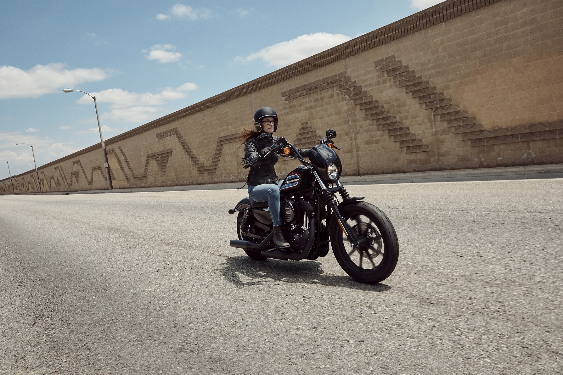Harley-Davidson Iron 1200 pilotada em movimento com seu tanque com grafismo retrô