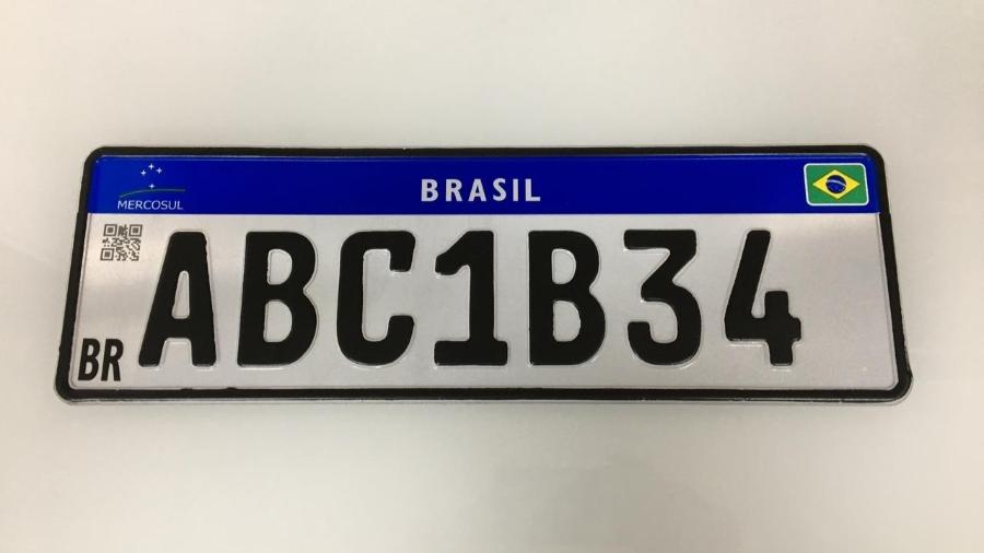 Foto mostra modelo da Placa Mercosul com numeração ABC1B34 tarja azul superior com nome e bandeira do Brasil