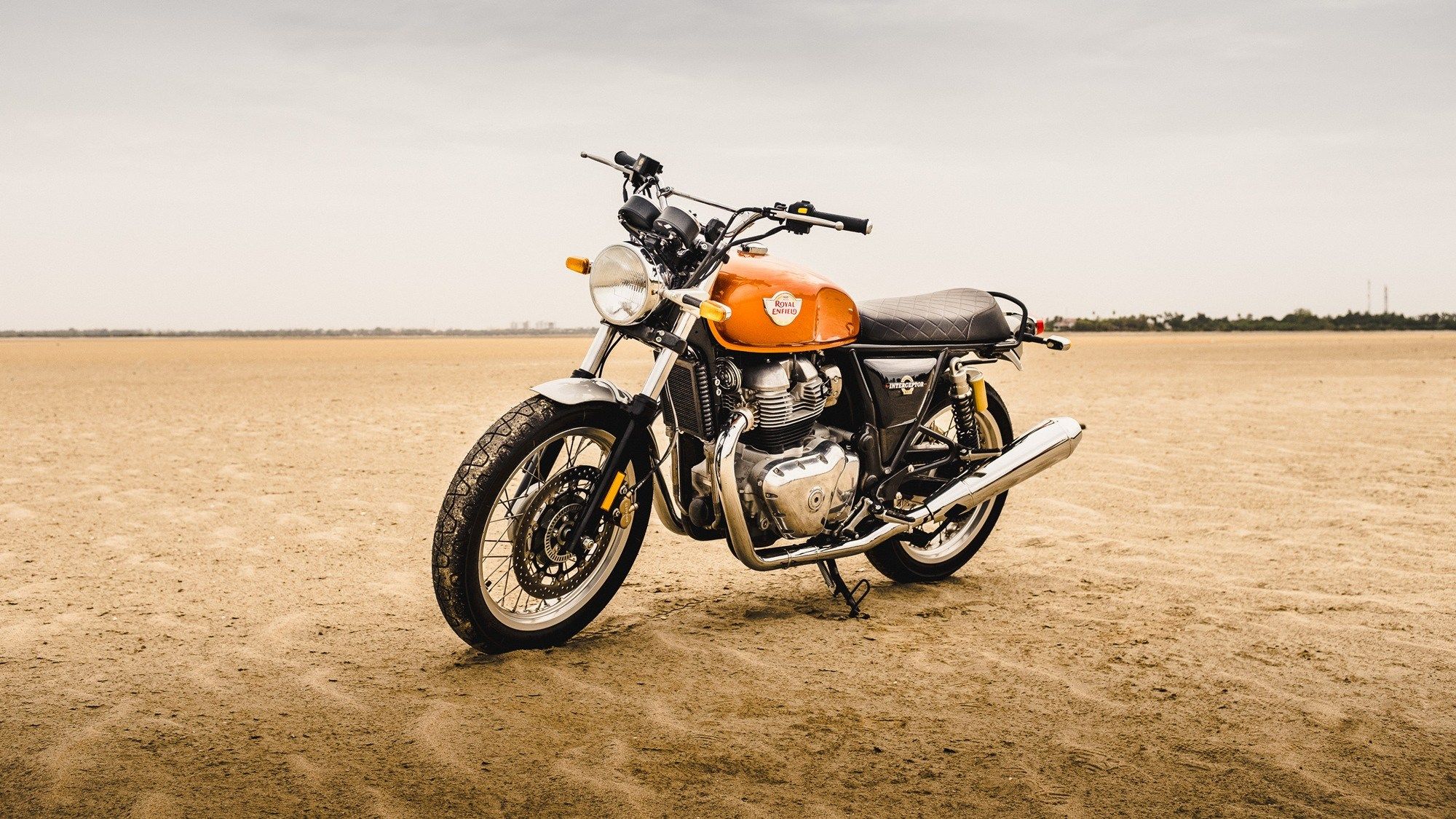 Royal Enfield Interceptor 650 com tanque laranja estática de frente em um ambiente de deserto
