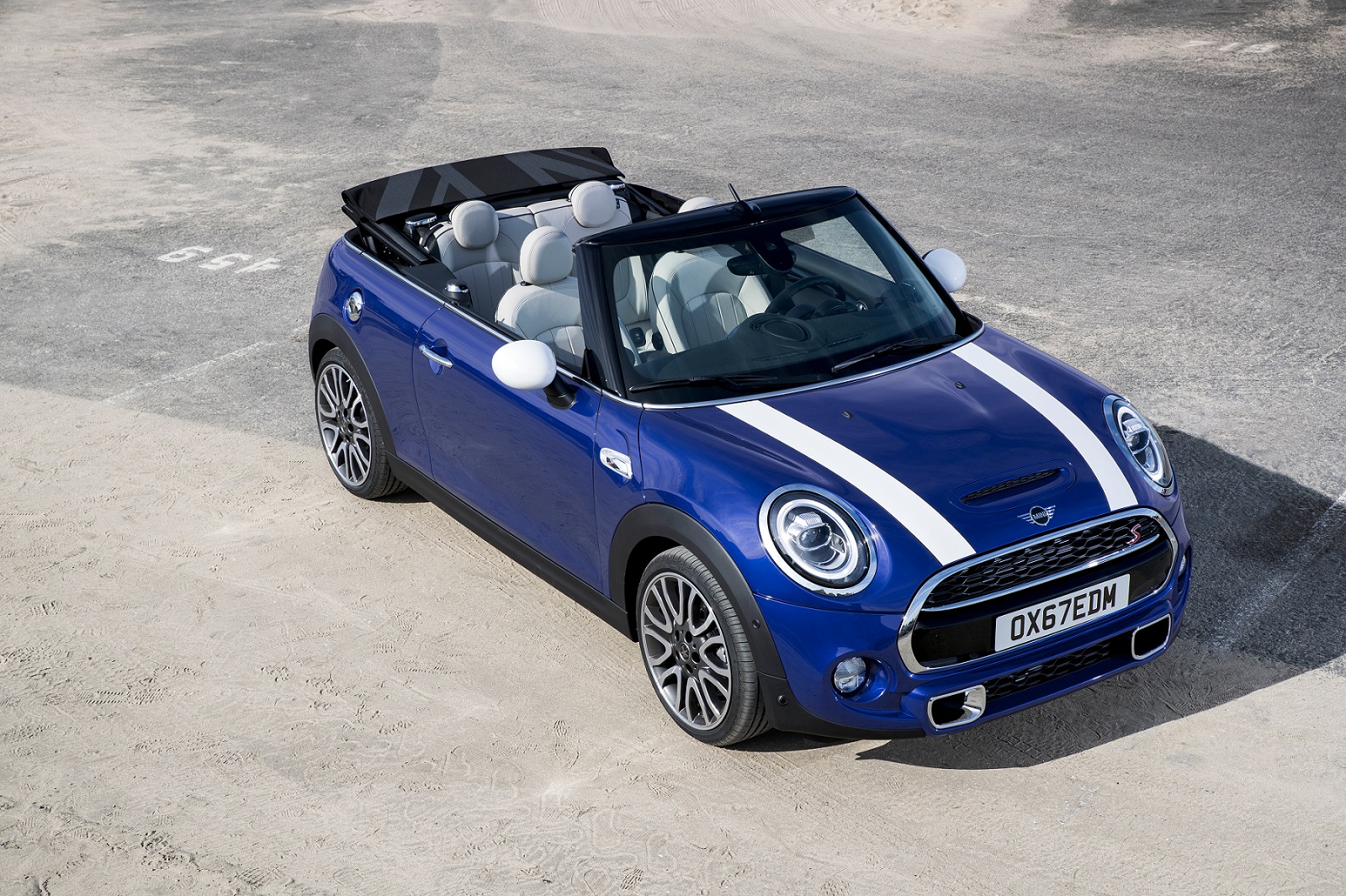 Mini Cooper Cabrio S visto do alto na cor azul, com duas faixas brancas sobre o capô e capota aberta