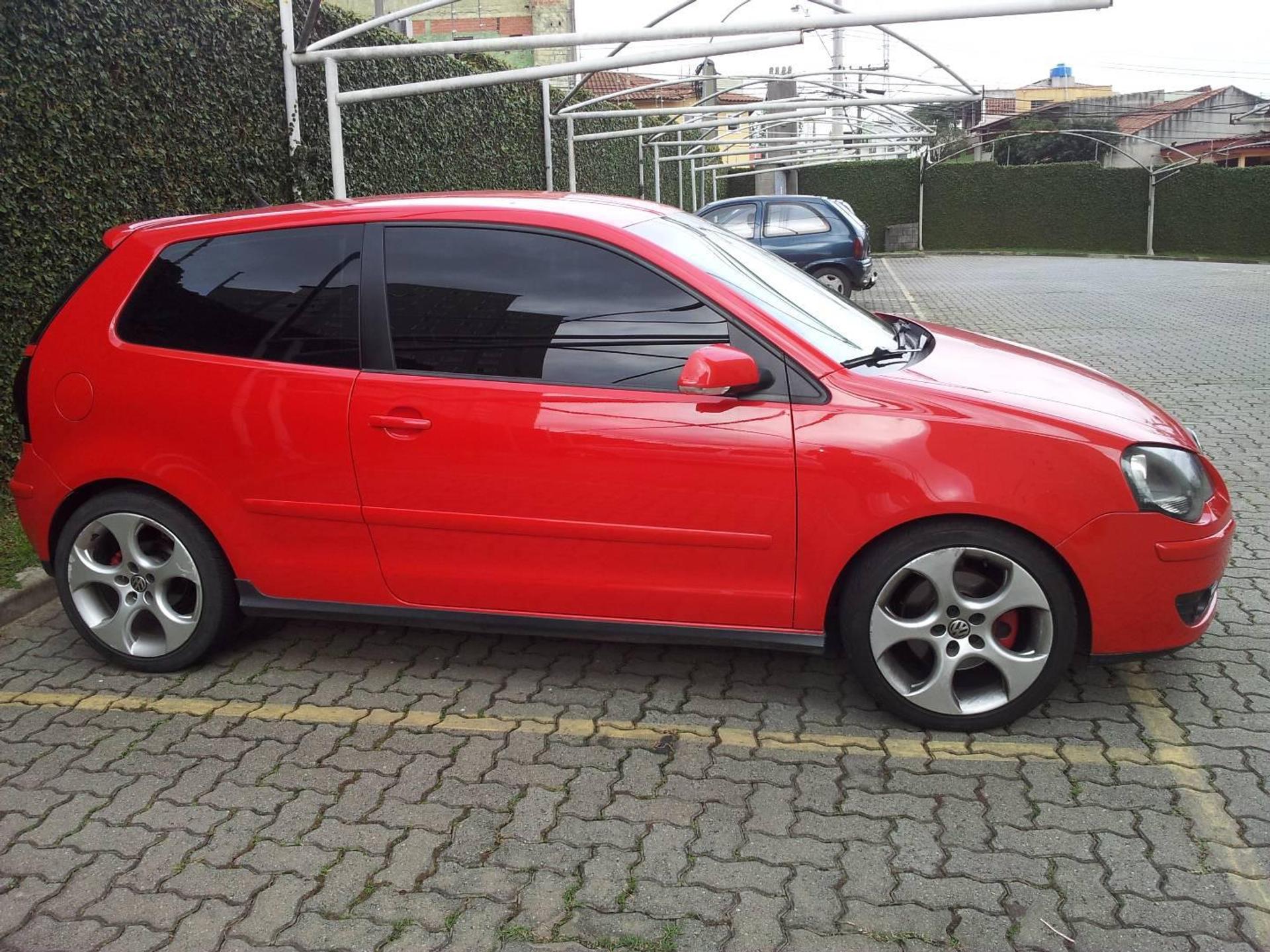 Polo GTI na cor vermelha estacionado e visto de perfil em um estacionamento aberto
