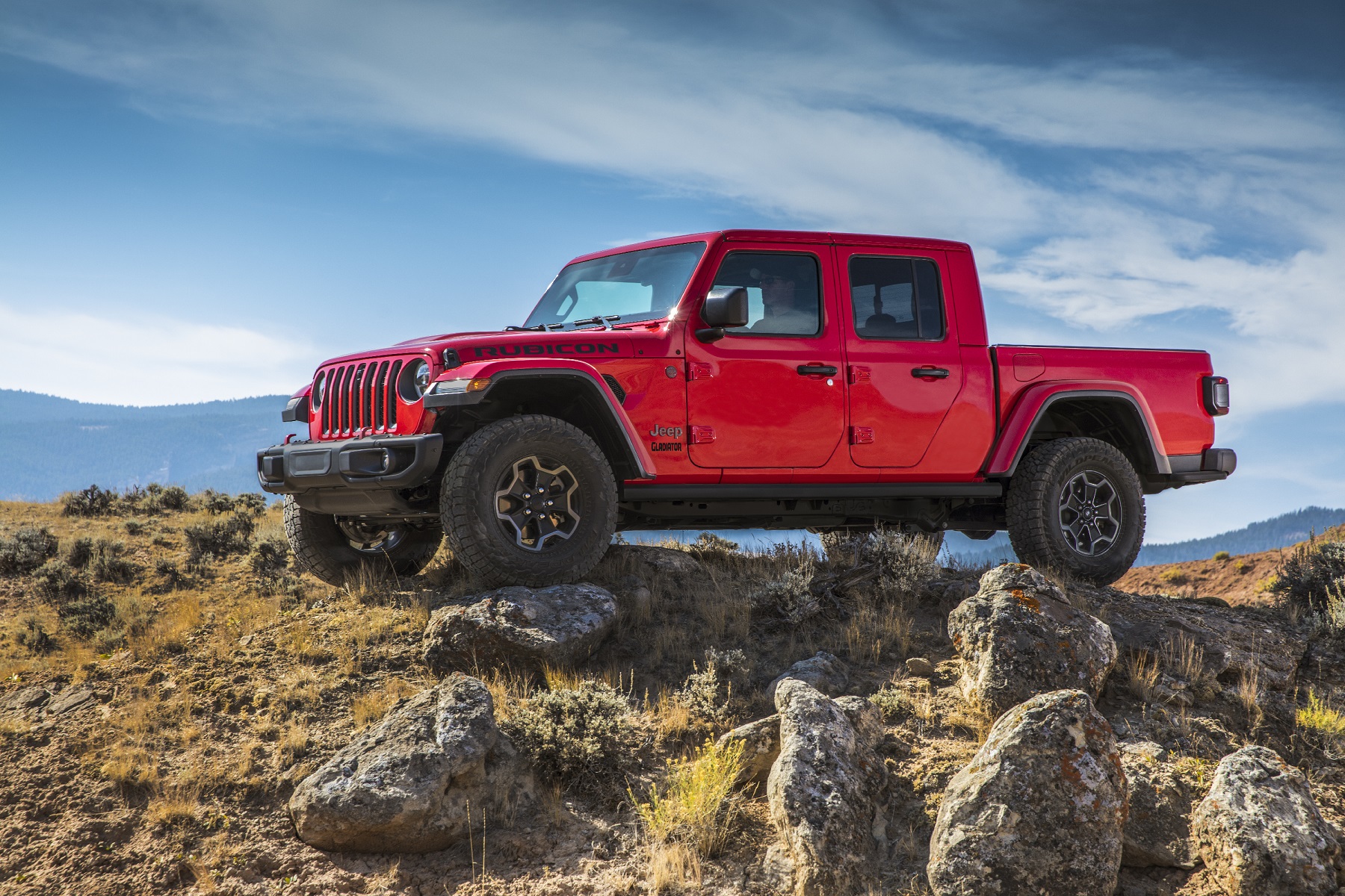 Picape Jeep Gladiator vermelha na versão RUbicon de perfil no alto de um penhasco