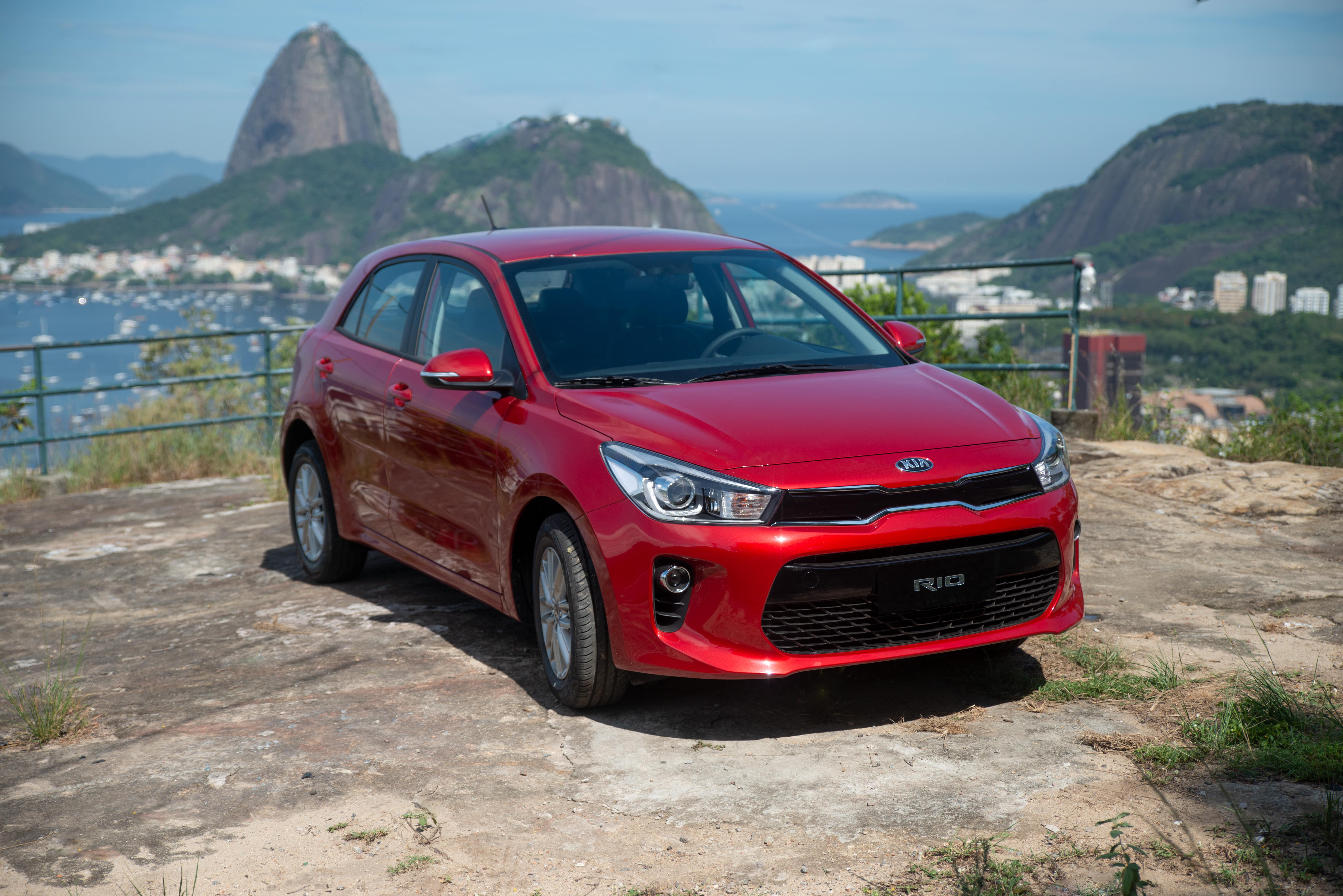Kia Rio vermelho de frente parado em mirante tendo ao fundo a enseada de Botafogo e o Pão de Açúcar , no Rio de Janeiro