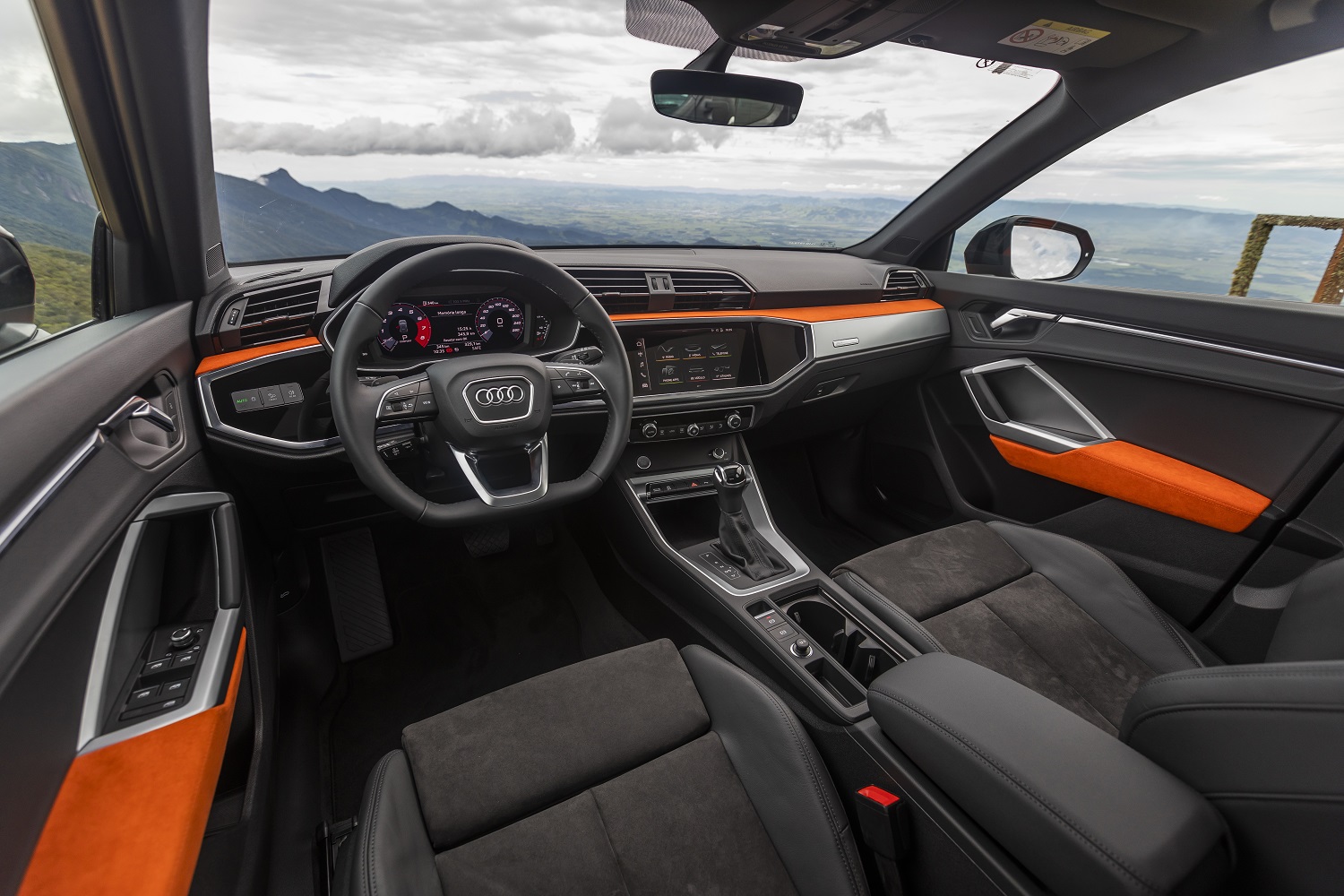 Audi Q3 com volante de base reta, detalhes de couro laranja nas portas e no painel