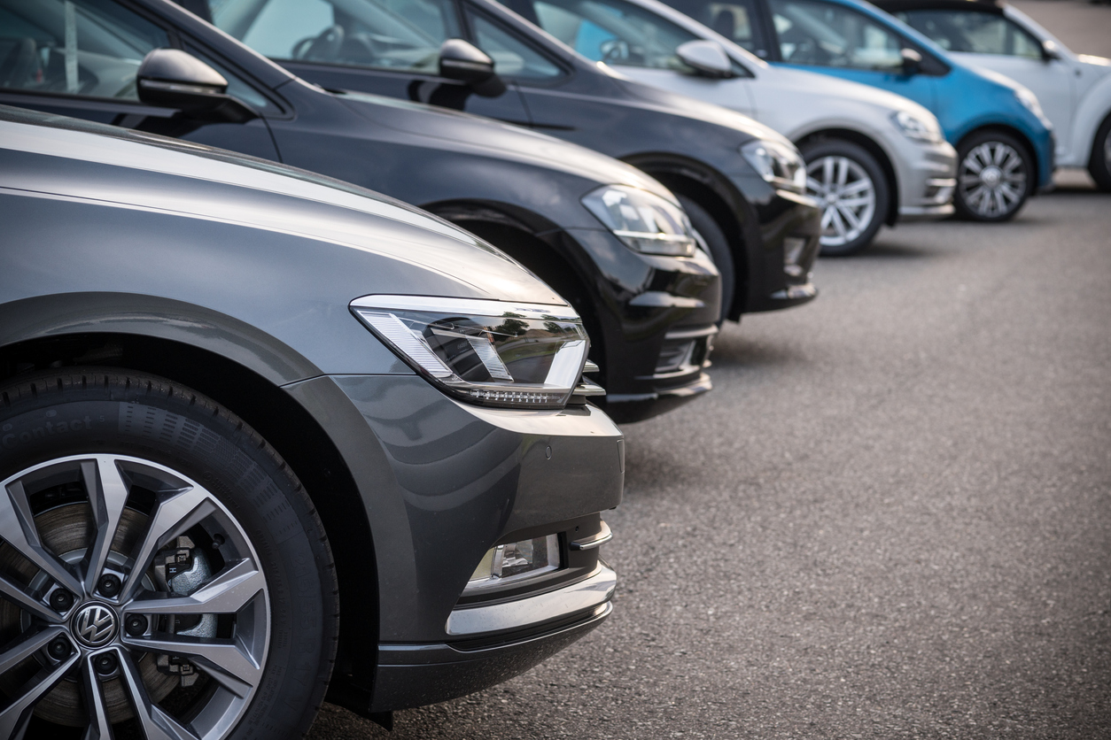 Imagem mostra apenas parte do capô e da roda de vários carros seminovos um ao lado do outro