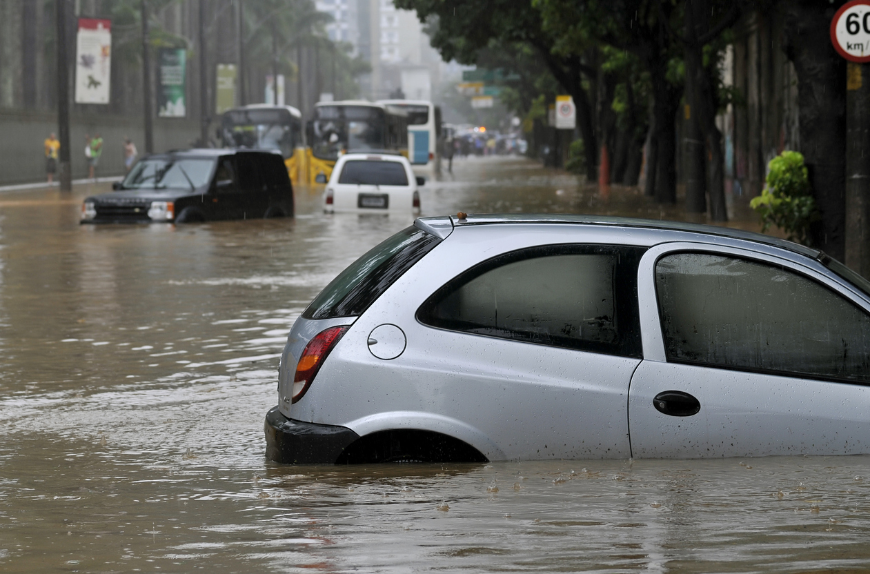 Um Chevrolet Celta aparece com água acima da roda em uma rua alagada