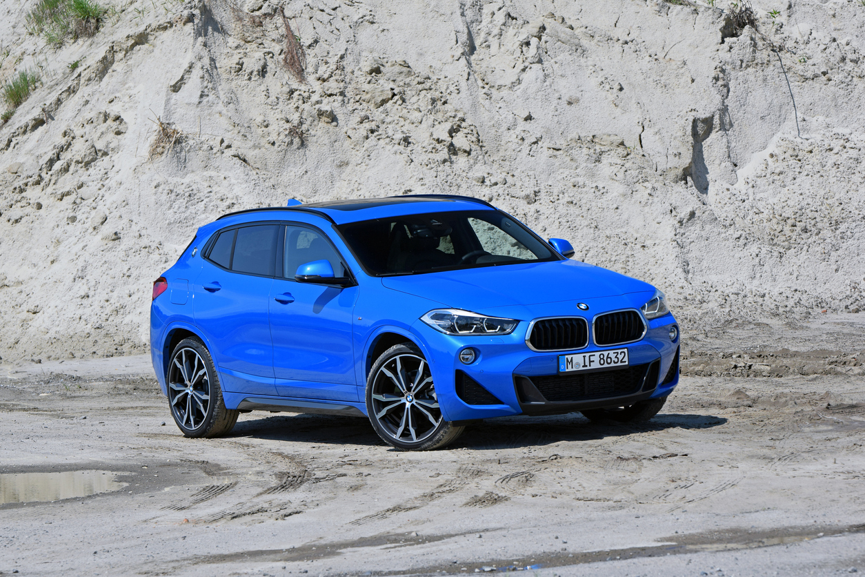 BMW X2 azul visto na diagonal e ambientadona estrada