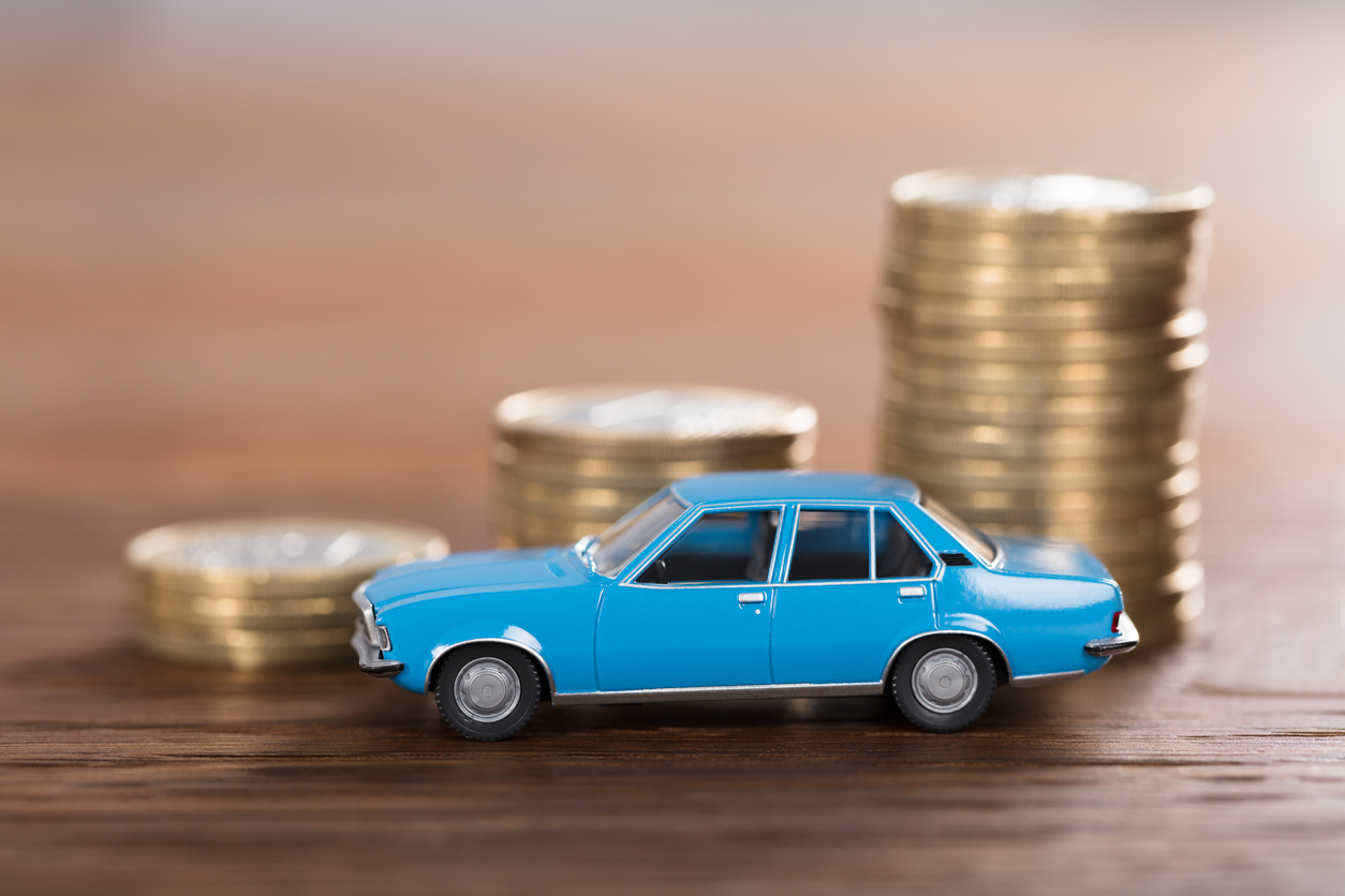 carrinho de brinquedo azul em frente a uma pequena pilha de moedas em cima da mesa