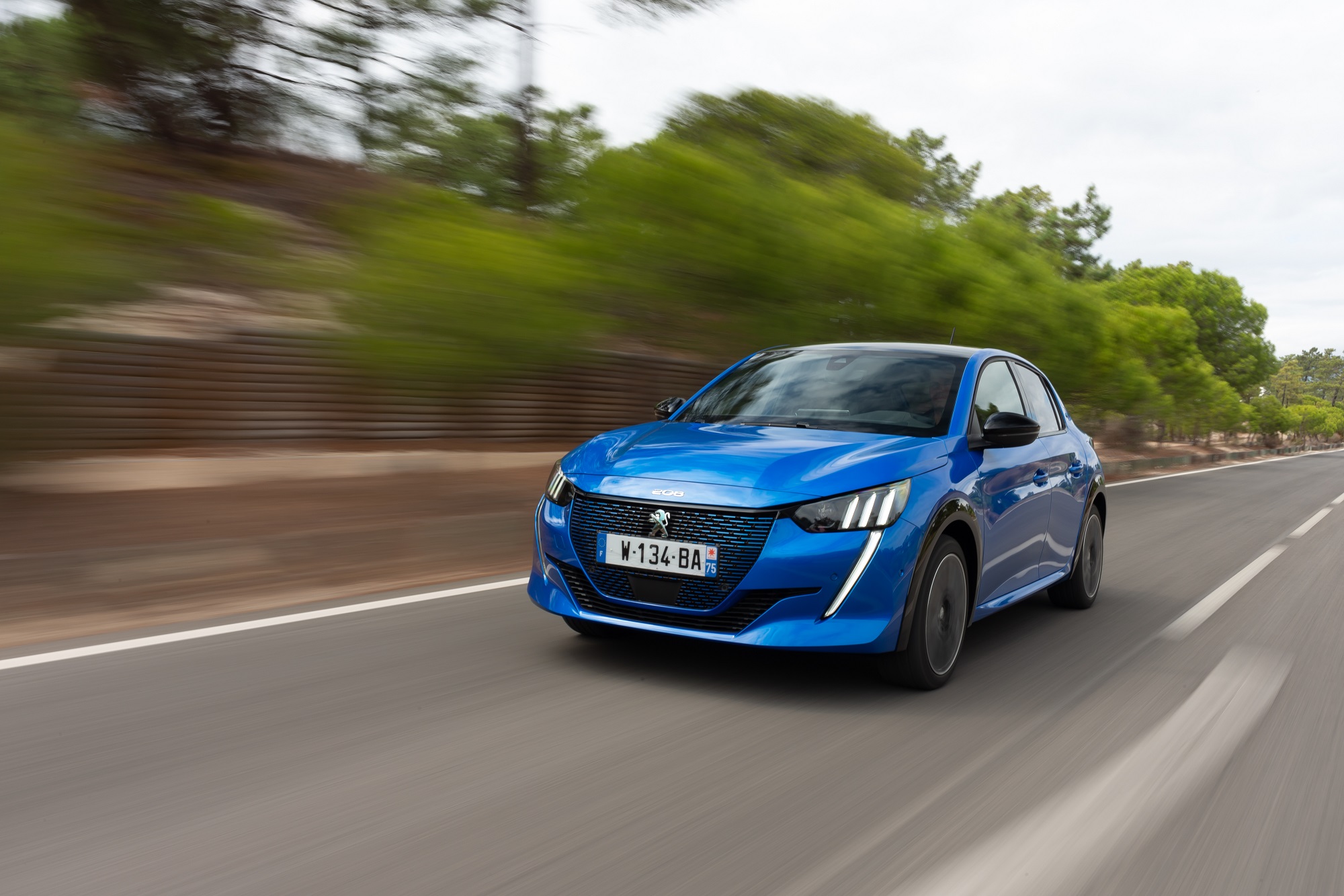 Peugeot E 208, a versão elétrica do hatch, na cor azul de frente e em movimento