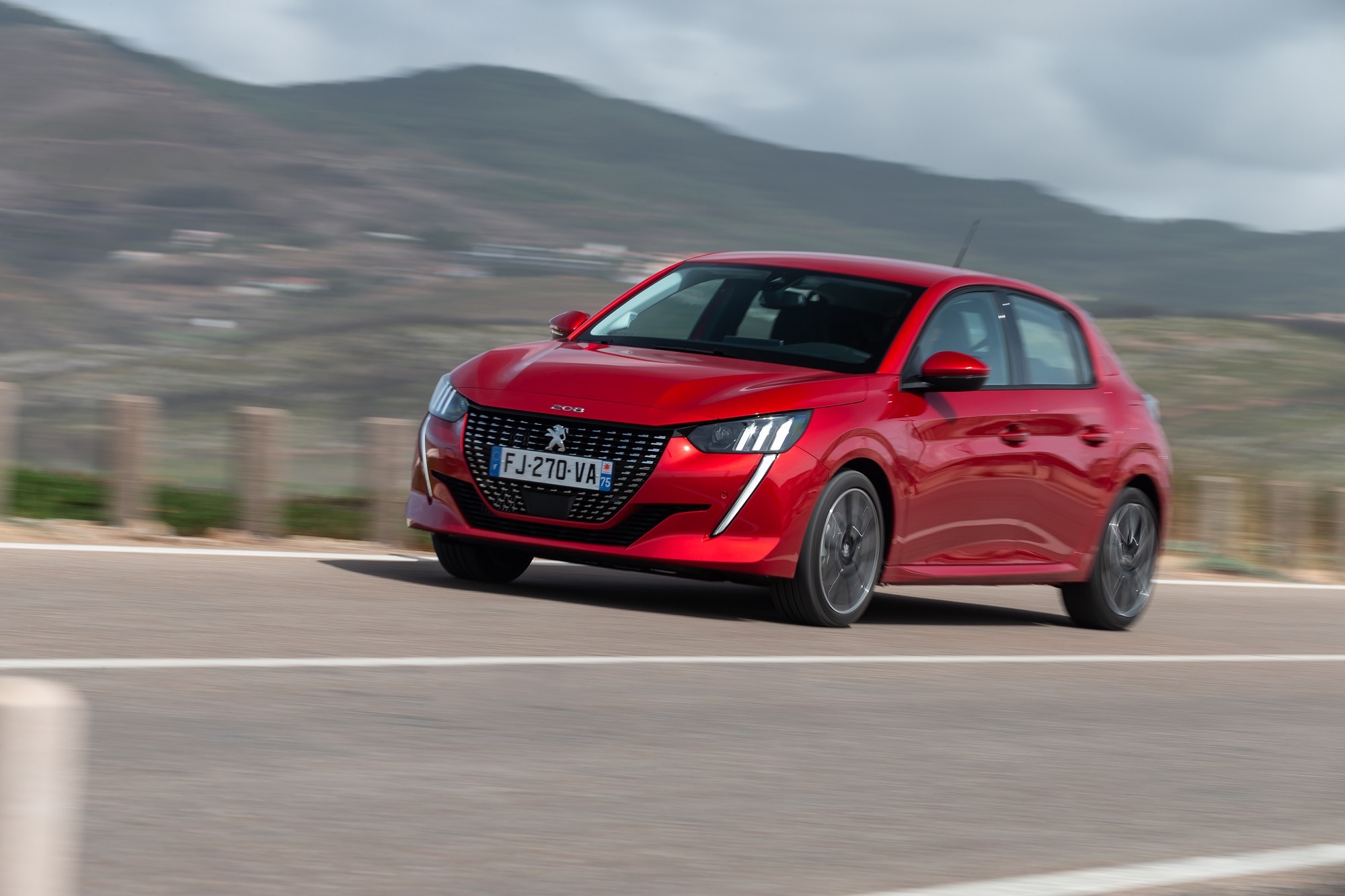 Novo Peugeot 208 vermelho em movimento em uma estrada