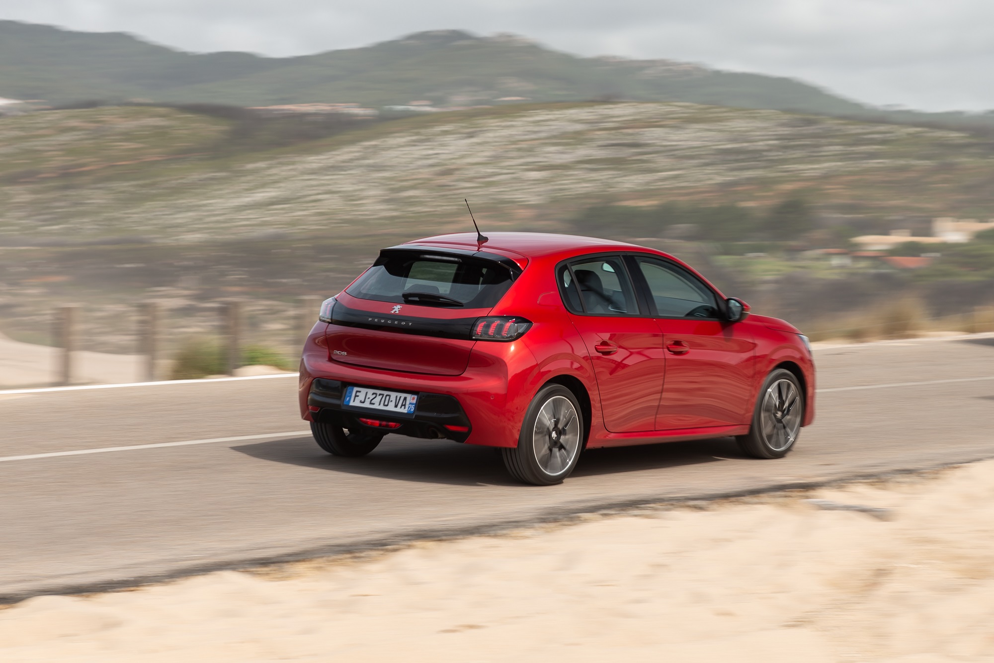 Novo Peugeot 208 de traseira em movimento na estrada na cor vermelha