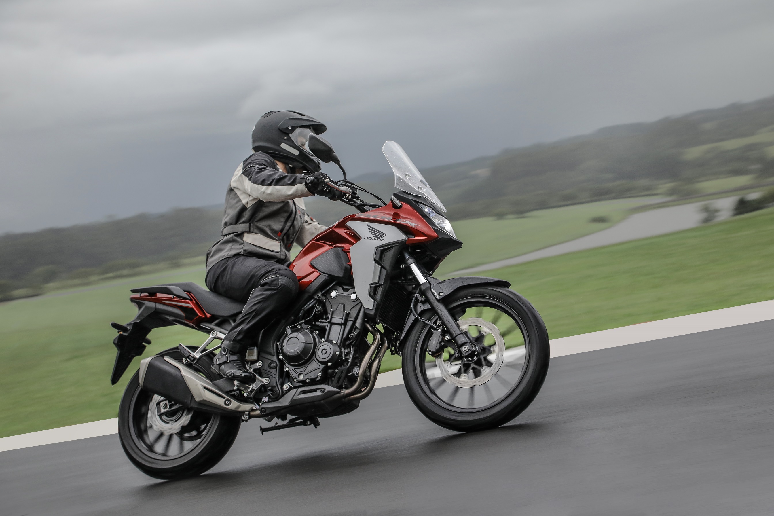 Honda CB 500X fazendo a curva com tanque vermelho