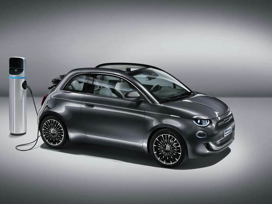 Fiat 500 Elétrico de perfil com teto aberto e sendo carregado na tomada pela traseira