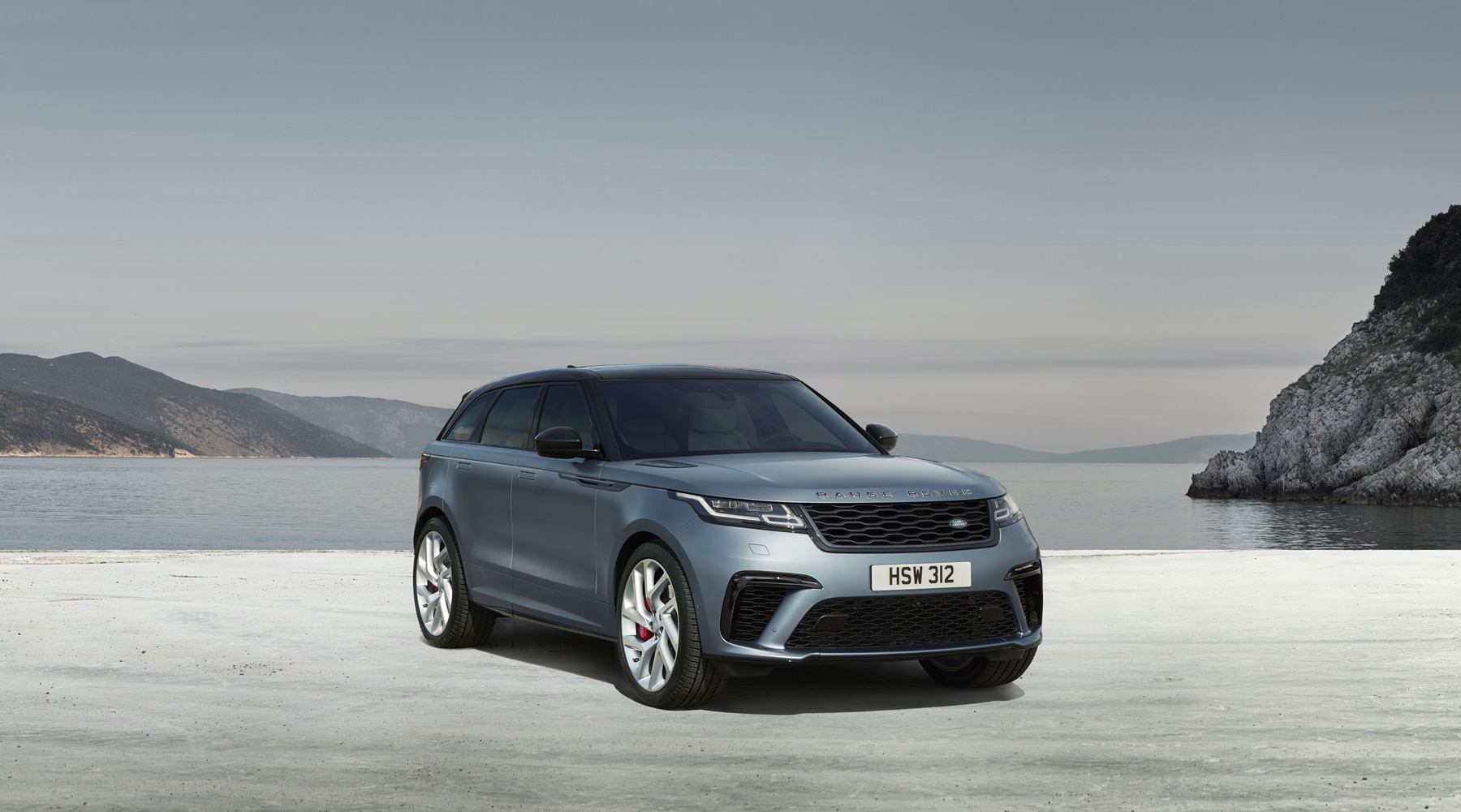 Range Rover Velar Sv autobiography na cor prata azulado de frente em uma praia de areia branca