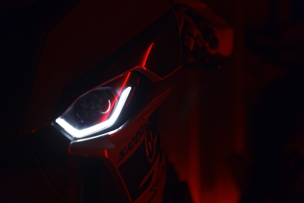 Detalhes dos faróis de LEDs acesos dentro das lentes da moto em um ambiente escuro