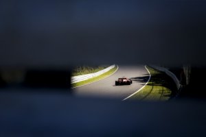 Foto de um carro de fórmula um no GP do Japão tirada da abertura de um guard rail