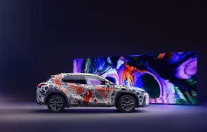 Lexus UX tatuado de perfil ao fundo um painel multiforma e multicolorido