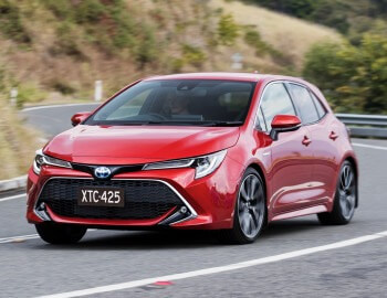 Toyota Corolla hatvh europeu na cor vermelha em movimento com morro gramado ao fundo