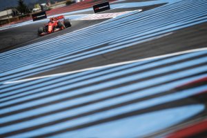 Imagem mostra oista com faixas azuis pintadas e ao fundo carros da F1 fazendo curvas em esse