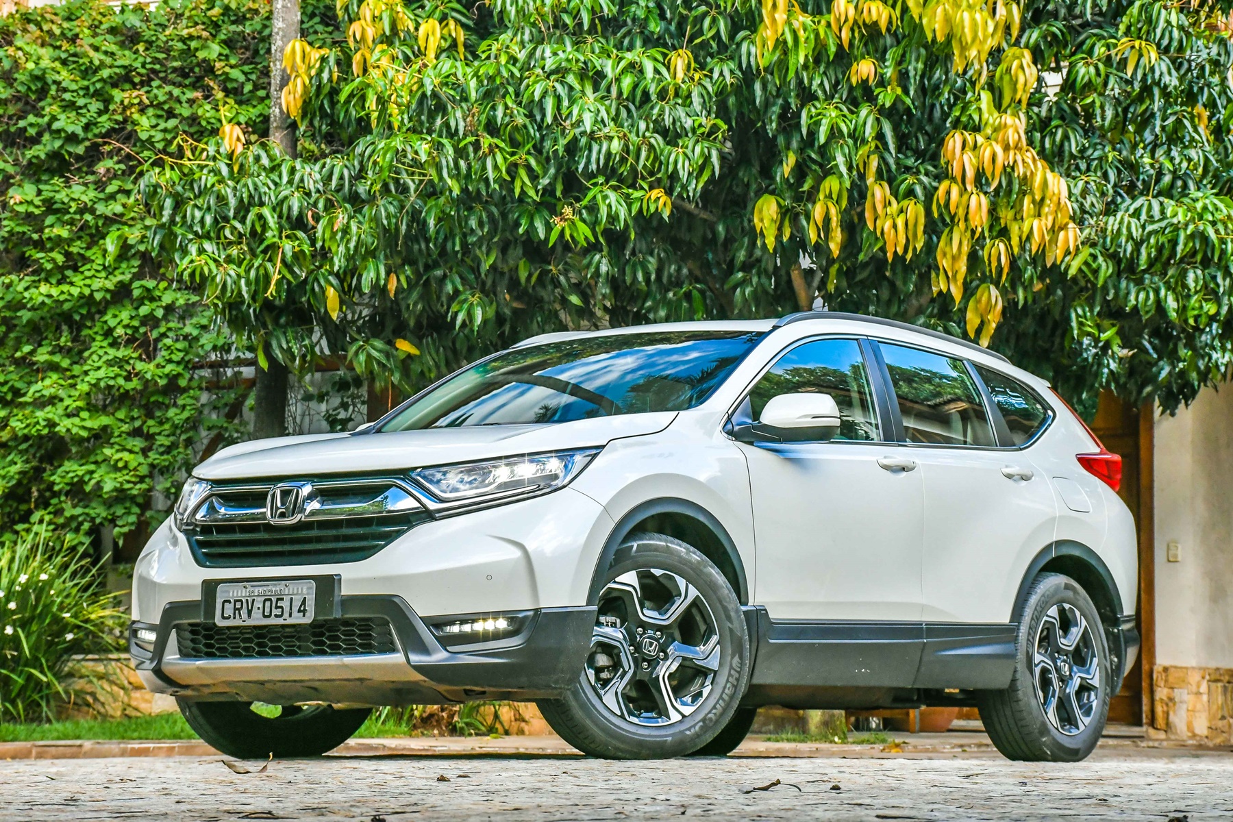 Honda CR-V branco de frente com árvores ao fundo
