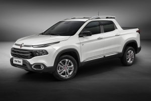 Fiat Toro branca na versão Volcano parada de perfil em estúdio com fundo cinza escuro
