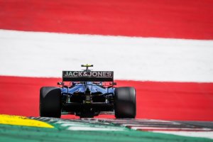 Carro de Fórmula 1 no Gp Da Áustria de 2019 tendo ao fundo um muro com a scores da bandeira vermelha e branca da Áustria