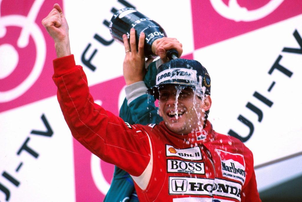 Ayrton Senna com macacão da McLaren no pódio recebendo banho de champanhe