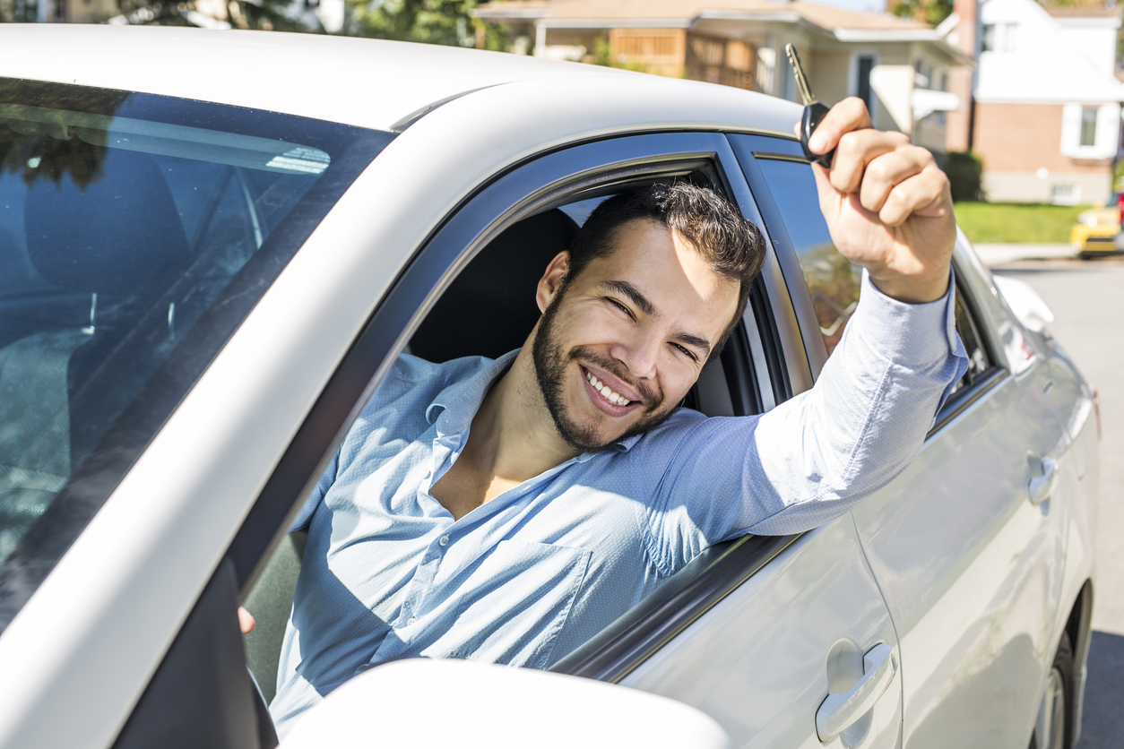 Homem da janela do carro com mão levantada e a chave do automóvel na mão