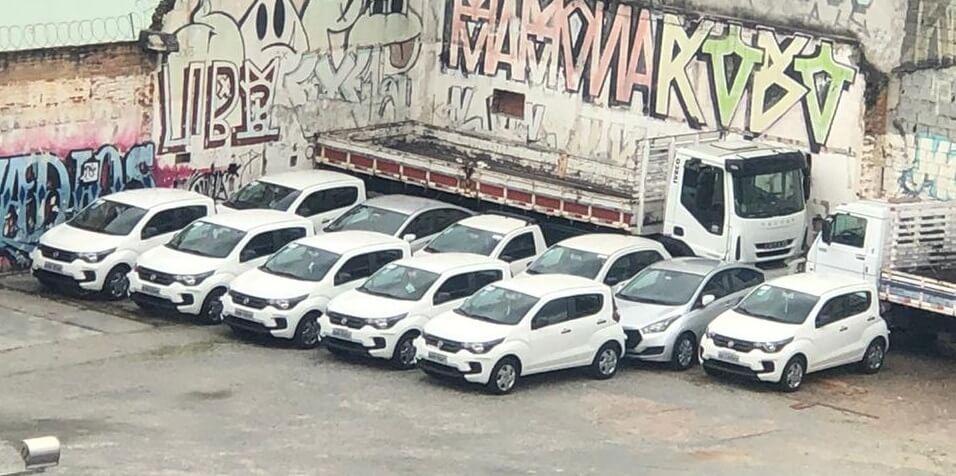 Frota de Fiat Mobi na cor branca e com grade escura lado a lado em um estacionamento