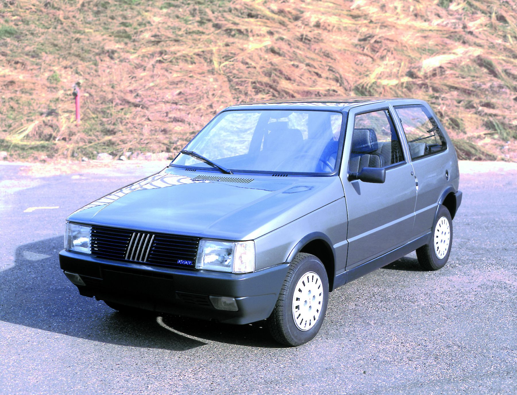 Fiat Uno Sx 194 azul de frente ao fundo um barranco sem grama
