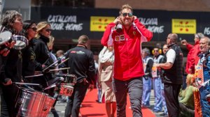Sebastian Vettel com jqueta da ferraroi e fones nos ouvidos caminhando