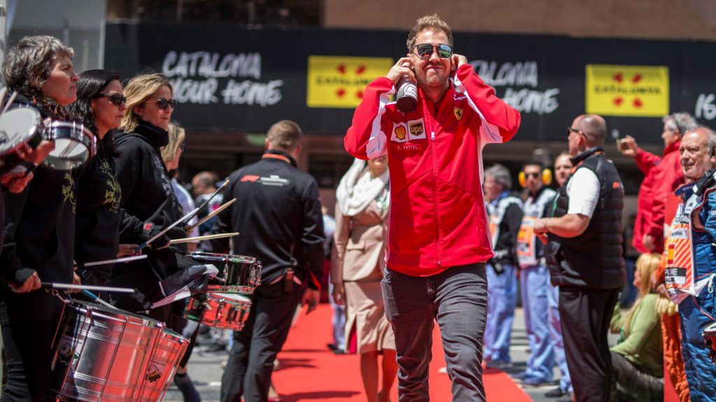 Sebastian Vettel com jqueta da ferraroi e fones nos ouvidos caminhando