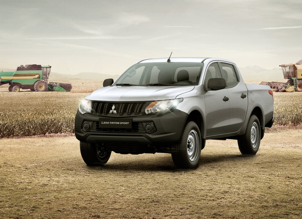Mitsubishi L200 Triton prata de frente em cenário de areia e pedras