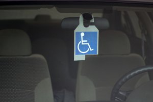 símbolo de PCD, em branco e azul, pendurado no espelho retrovisor de um carro