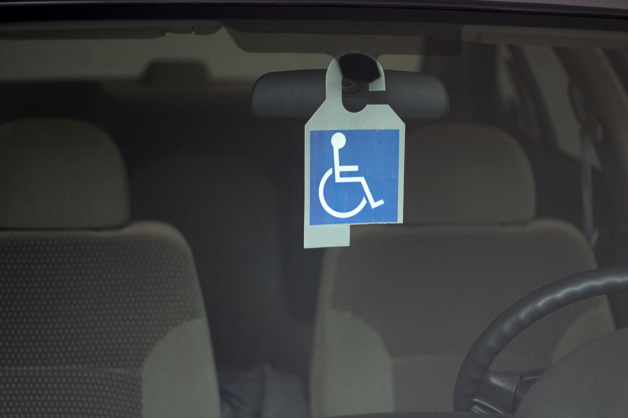 símbolo de PCD, em branco e azul, pendurado no espelho retrovisor de um carro