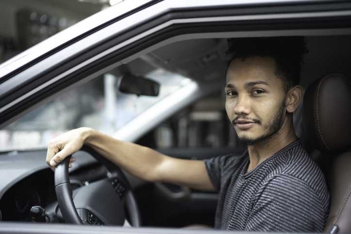 Jovem dirigindo carro e olhando para a foto