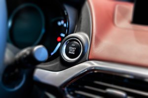 Sistema start stop de um carro em destaque com restante do painel ao fundo desfocado