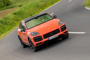 Porsche Cayenne Coupé Turbo laranja em movimento numa curva de estrada em close diagonal