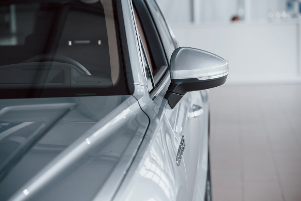 Left Side. Particle View Of Modern Luxury White Car Parked Indoors At Daytime